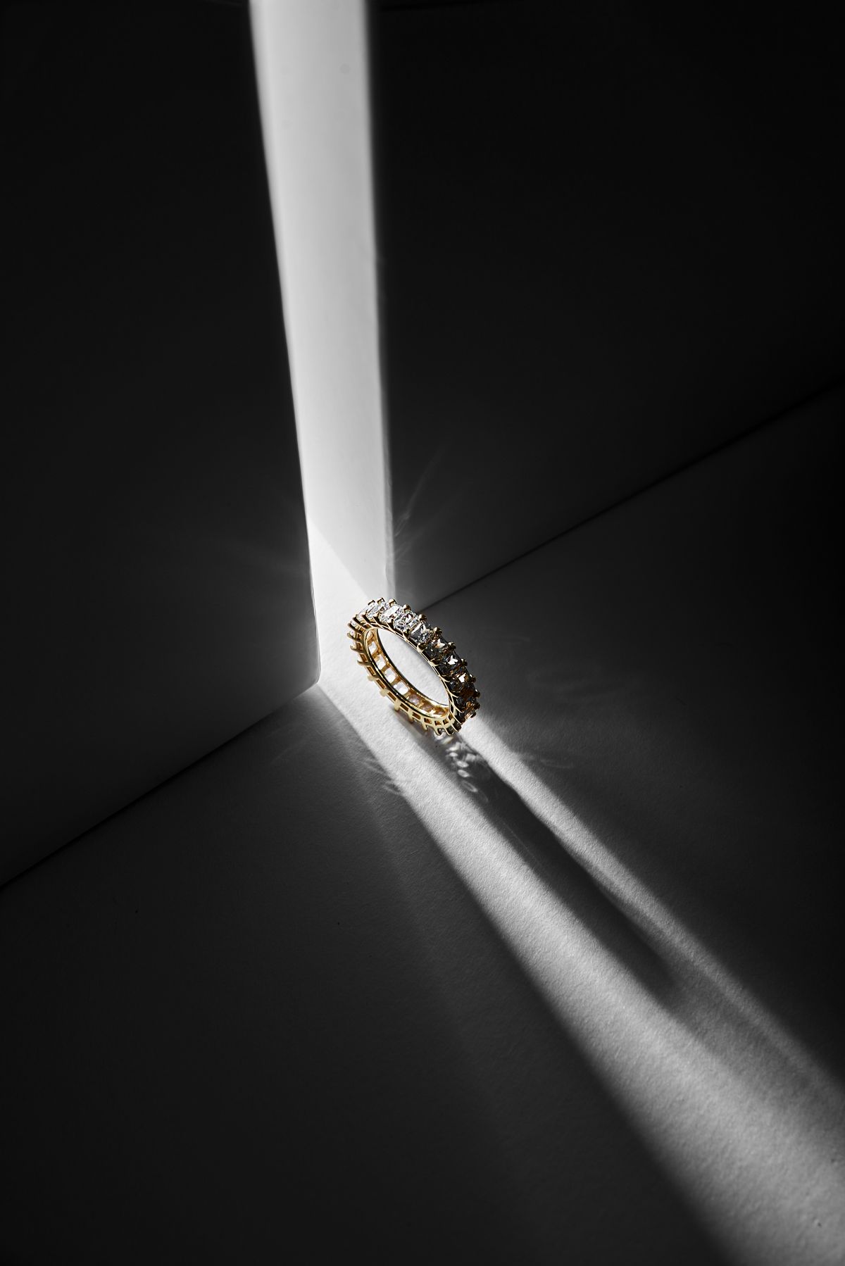 Radiant-cut eternity band in a beam of studio light