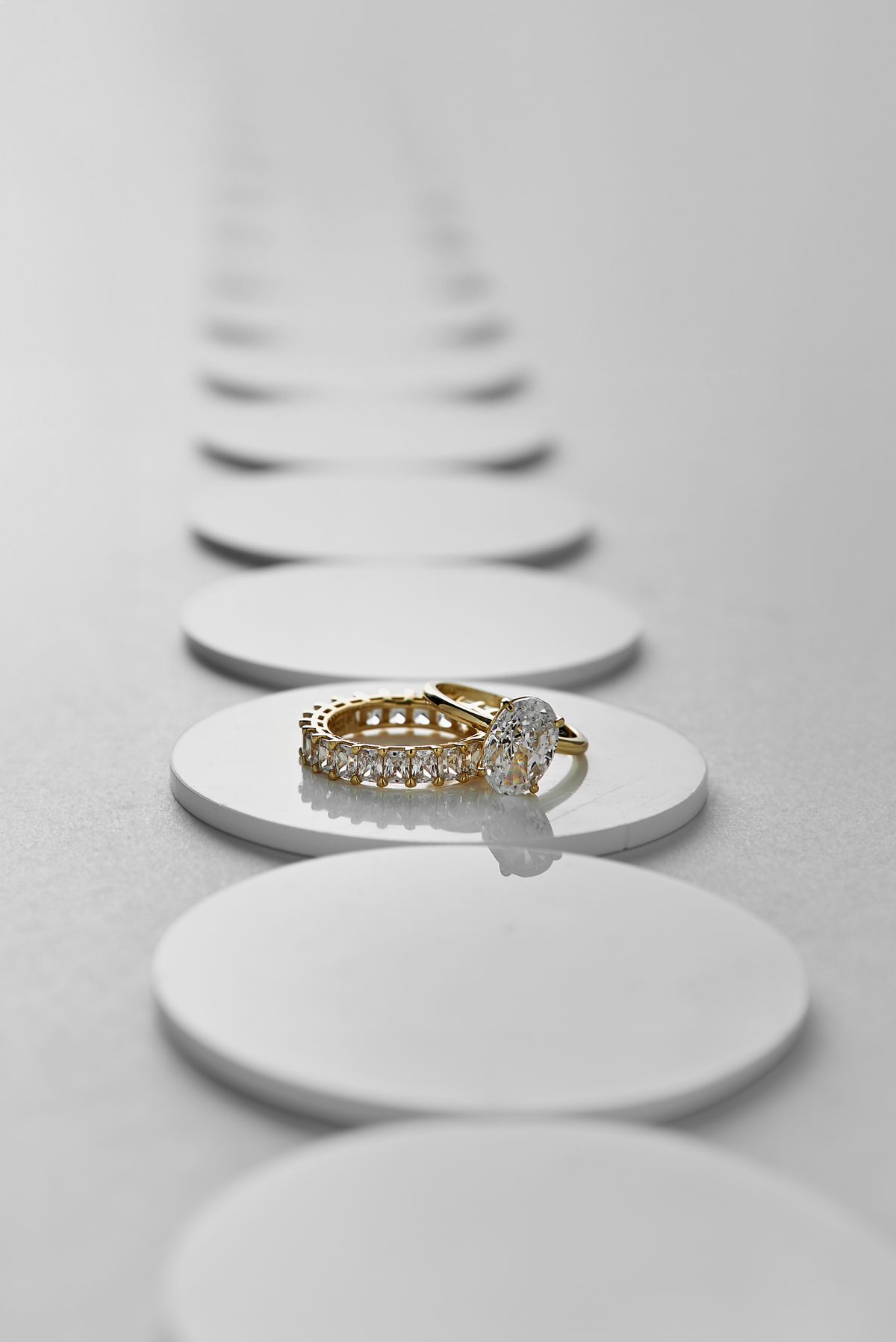 Oval solitaire and eternity band in yellow gold on white pedestals
